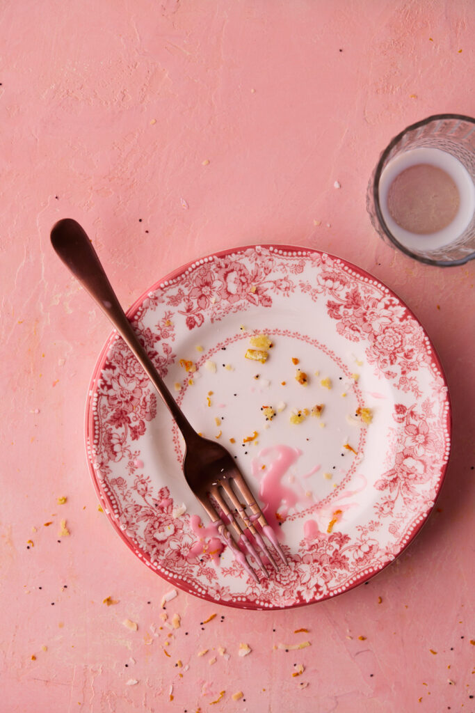 Empty dessert plate with crumbs and pink glaze after enjoying a slice of Blood Orange Coconut Bundt Cake