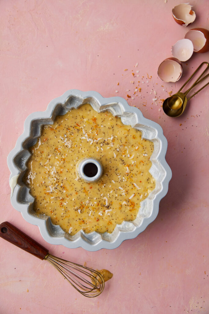 Bundt pan filled with Blood Orange Coconut Cake batter with poppy seeds before baking.